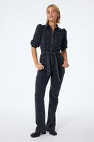 Scamp and Dude Washed Black Denim Wide Leg Jumpsuit | Model wearing a washed black jumpsuit that features a zip front detail and belt.