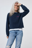 Scamp and Dude Washed Navy Cropped Sweatshirt | Model wearing navy cropped sweatshirt with light blue distressed jeans and white t shirt.