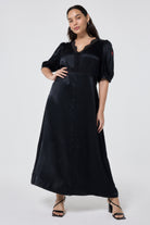 Scamp and Dude Black with Lace Trim Satin Puff Sleeve Midi Tea Dress | Model wearing a black satin midi tea dress featuring lace trim detail paired with black heels.