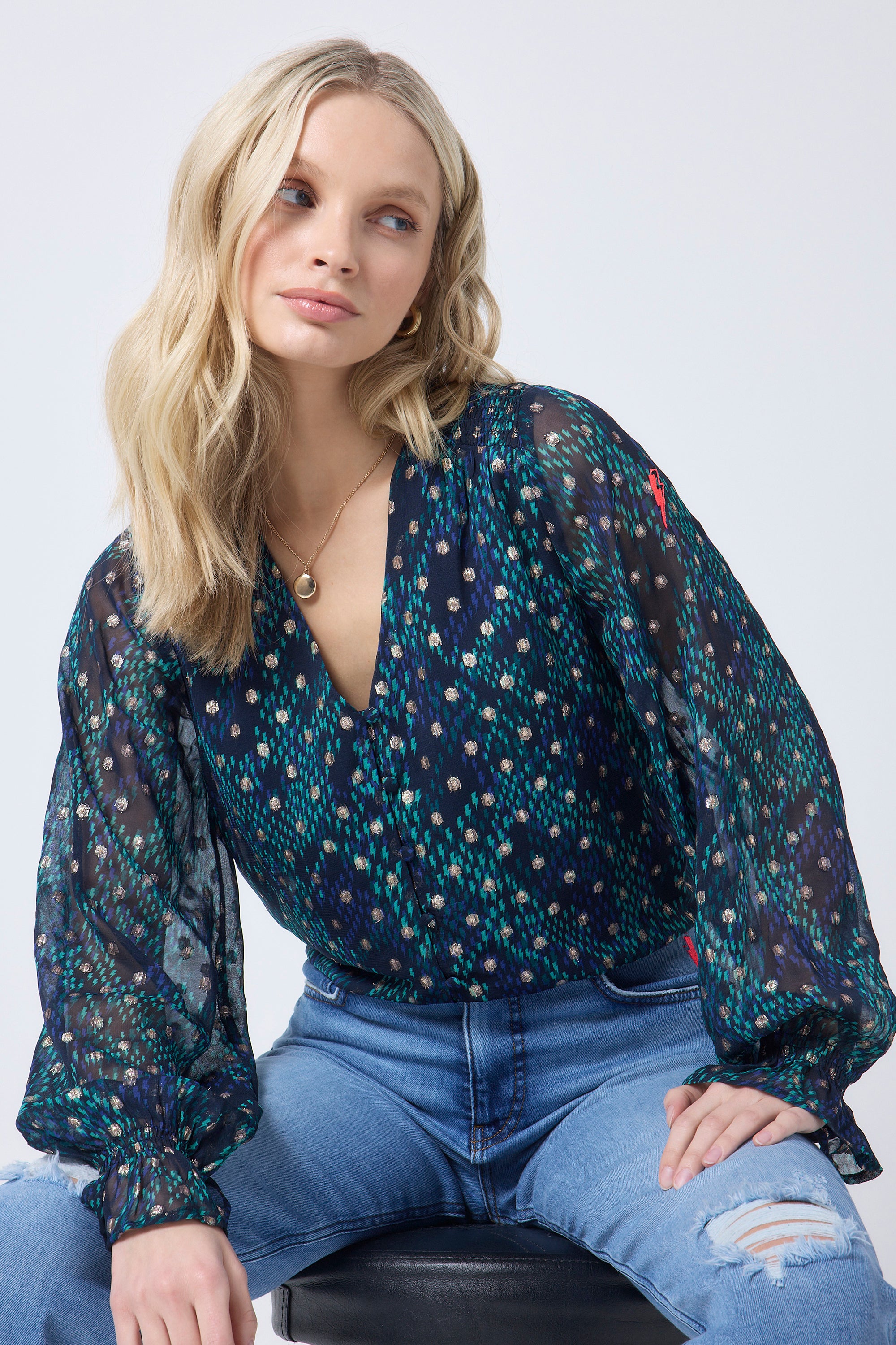 Scamp and Dude Navy with Green and Gold Foil Lightning Bolt Snake Print Flute Sleeve Blouse | Model wearing a navy blouse with green and gold snake print, paired with distressed blue jeans.