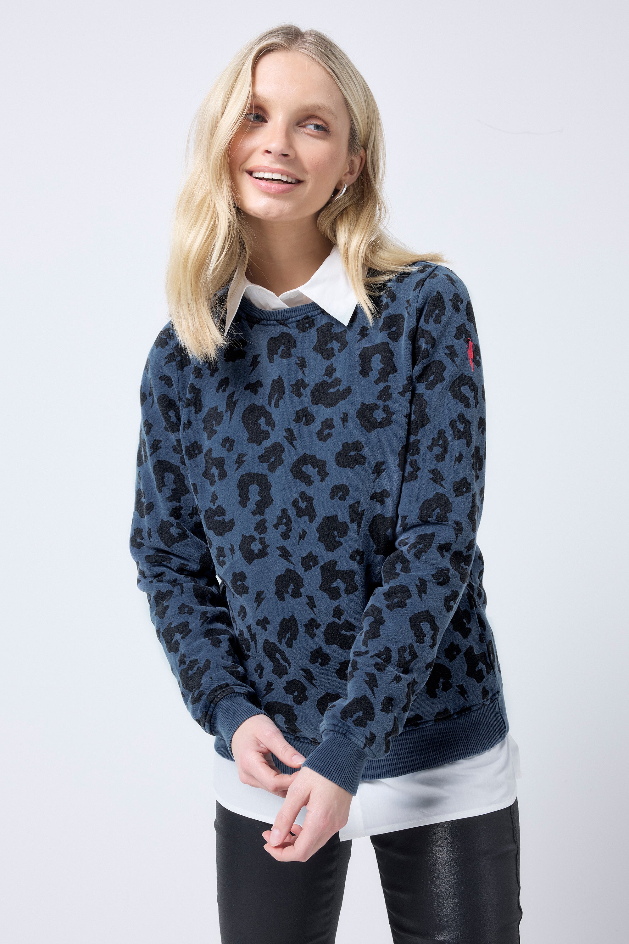 Scamp and Dude Navy with Black Leopard Classic Sweatshirt | Model wearing a navy sweatshirt with black leopard print over a white shirt. Worn with black coated jeans.