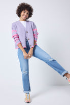 Scamp and Dude Lilac and Pink Stripe Cardigan | Model wearing a lilac cardigan with pink stripe detail, paired with blue jeans and a white t shirt.