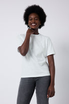 Scamp and Dude White Studded Relaxed Band T-Shirt | Model wearing short sleeve white t-shirt with stud detail, paired with a pair of washed black jeans.