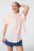 Scamp and Dude Coral and White Stripe Frill Sleeve Shirt | Model wearing coral and white stripe shirt featuring frill sleeves and paired with scallop hem denim shorts.