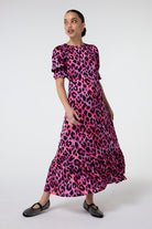 Scamp and Dude Pink and Lilac with Black Shadow Leopard Flute Sleeve Midi Dress | Model wearing a pink and lilac round neck midi dress in a black shadow leopard print. The dress features flute sleeves and has been paired with black pumps.