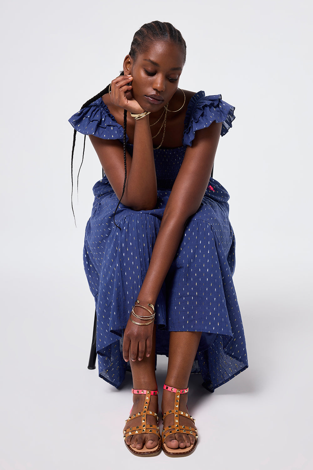 Air & Grace x Scamp & Dude Tan and Coral Leather Studded Gladiator Sandals | Model wearing a navy sundress with lurex spot detail paired with tan and coral leather studded gladiator sandals.