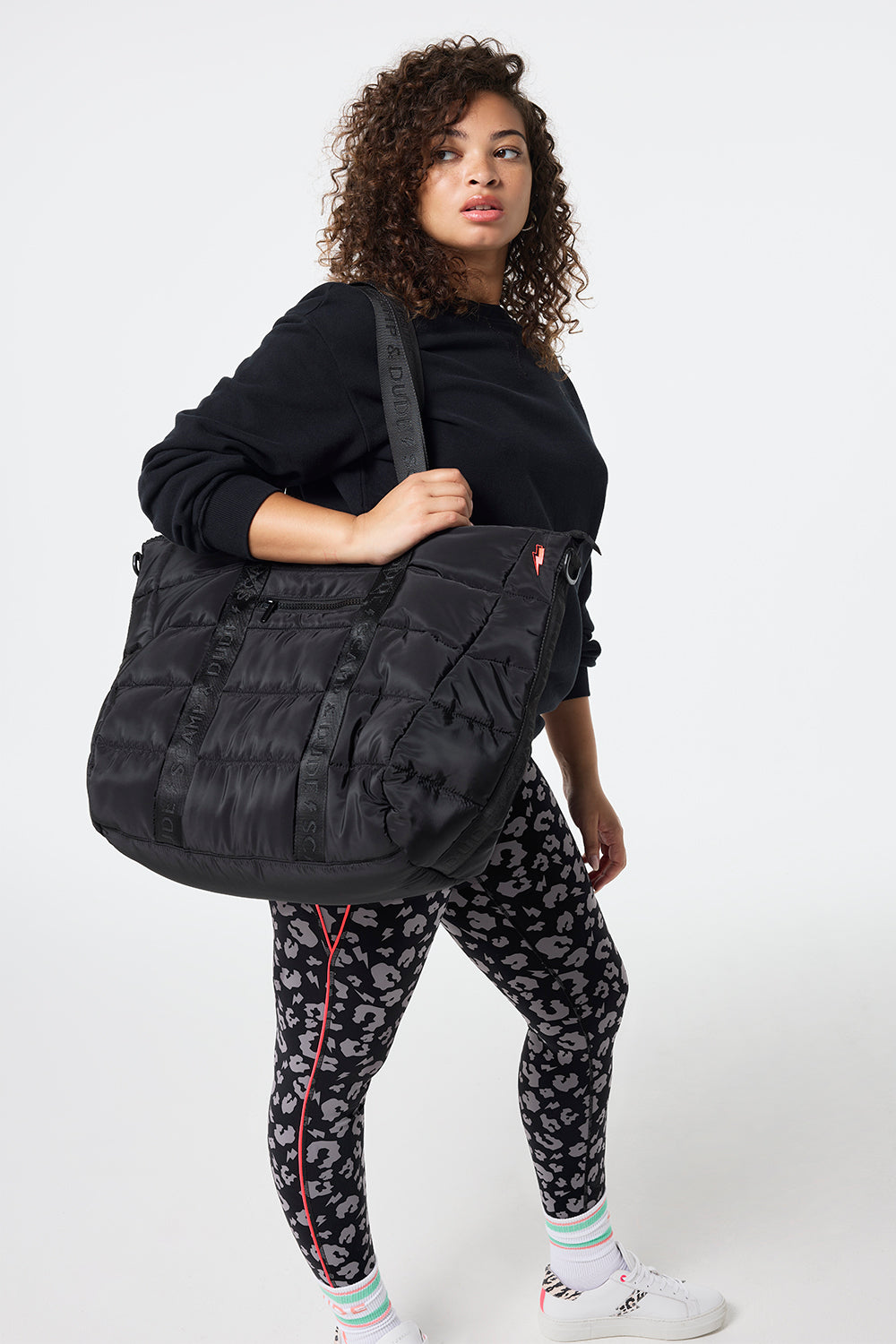 Scamp and Dude Black Large Puffa Tote Bag | Model wearing activewear leggings and a sweatshirt, holding a large black puffa tote bag.