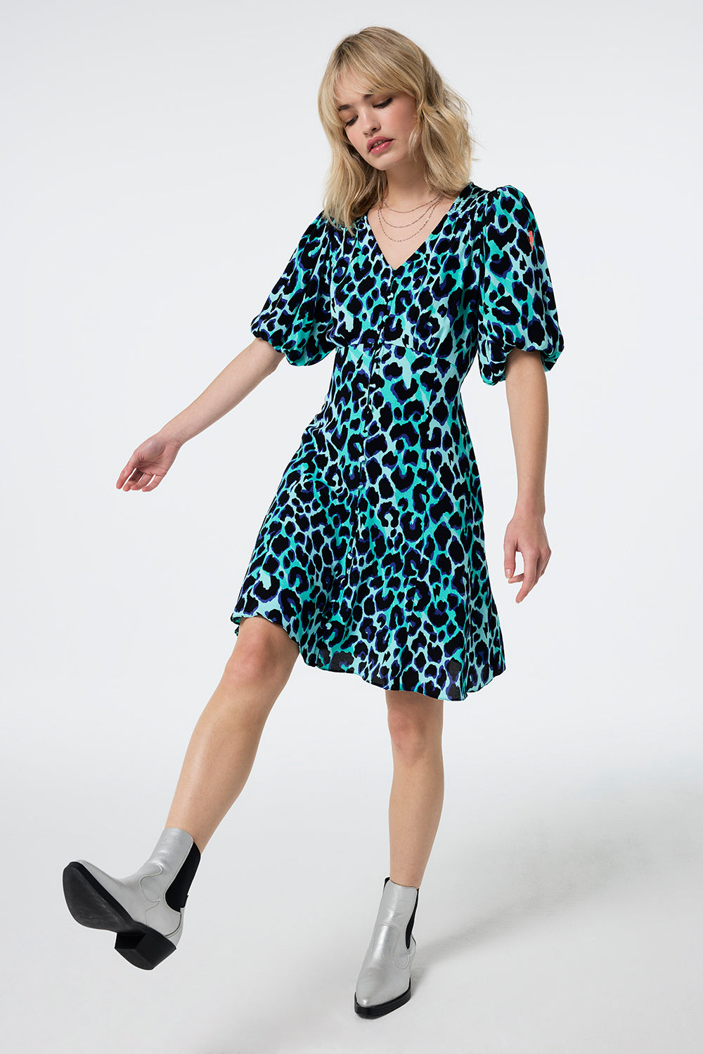 Scamp and Dude Turquoise with Black and Blue Shadow Leopard Puff Sleeve Short Tea Dress | Model wearing a turquoise short puff sleeve tea dress with black and blue shadow leopard print paired with silver boots.