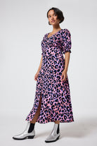 Scamp and Dude Pink with Blue and Black Shadow Leopard Flute Sleeve Midi Tea Dress | Model wearing a v neck pink leopard print tea dress with silver boots.