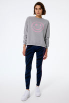 Scamp and Dude Navy with Black Graphic Tiger Print Full Length Active Leggings | Model wearing a grey smiley sweatshirt with navy full length leggings featuring black tiger print and neon pink details. Paired with chunky white trainers.