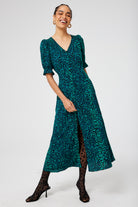 Scamp and Dude Green with Black Wild Leopard Flute Sleeve Midi Tea Dress | Model wearing a green midi tea dress with leopard print tights and black heels.